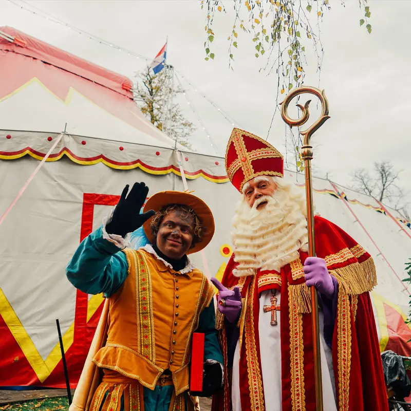 Sinterklaas en een Piet bij de ingang van de circustent